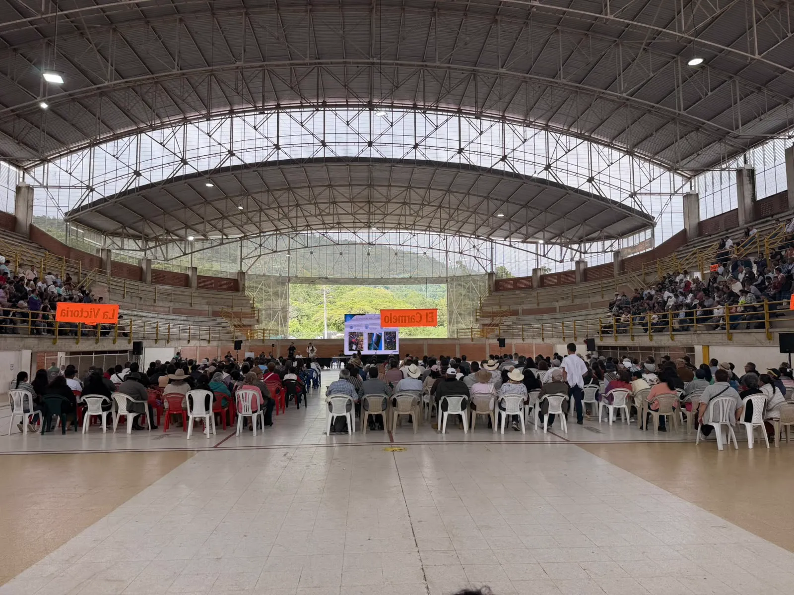 Asamblea de copropietarios en un coliseo cubierto con pantalla gigante, operada por CLICK