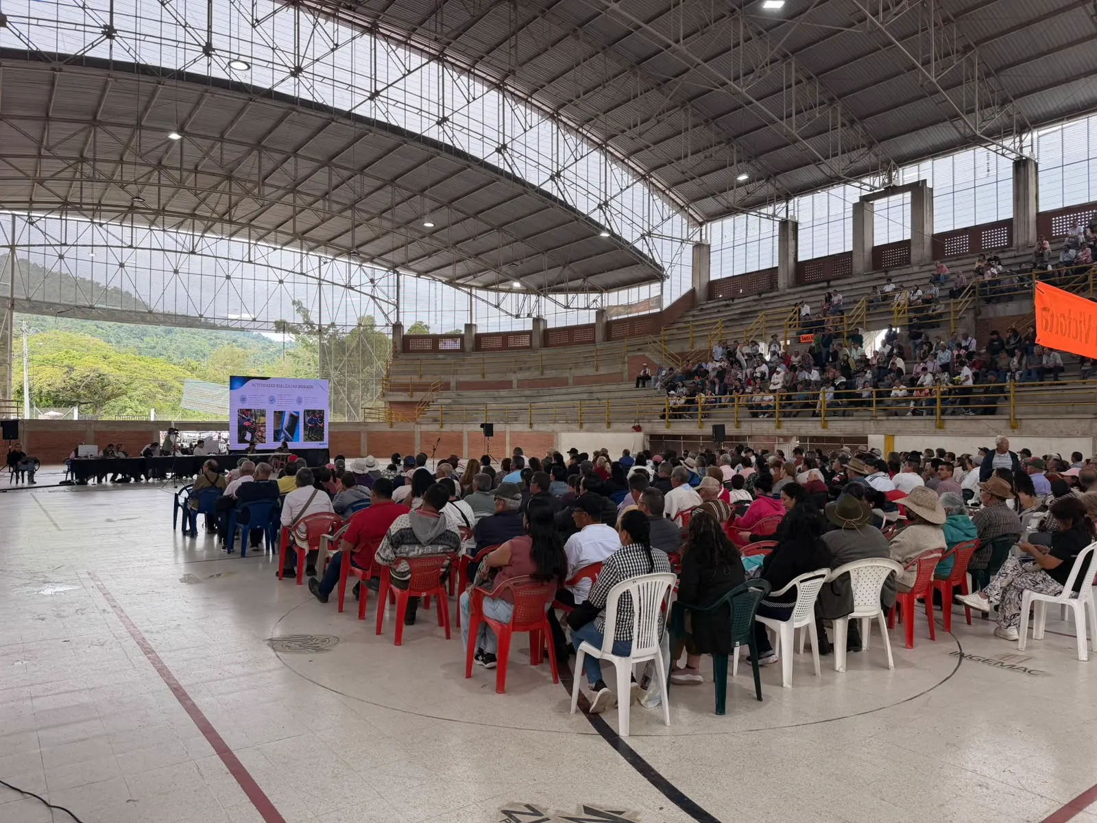 Asamblea en coliseo con pantalla para todo el público. CLICK, logística y votación electrónica para asambleas.
