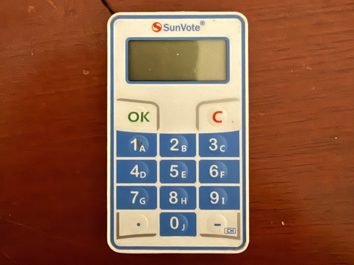 Control de votación electrónica de CLICK sobre una mesa de madera: teclado numérico, botones OK y C y pantalla apagada; el aparato que se asigna a una unidad y a su coeficiente desde la base de propietarios
