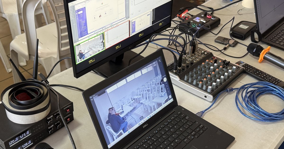 Mesa técnica de CLICK en una asamblea: computadores, consola de sonido y monitor con las vistas de cámara