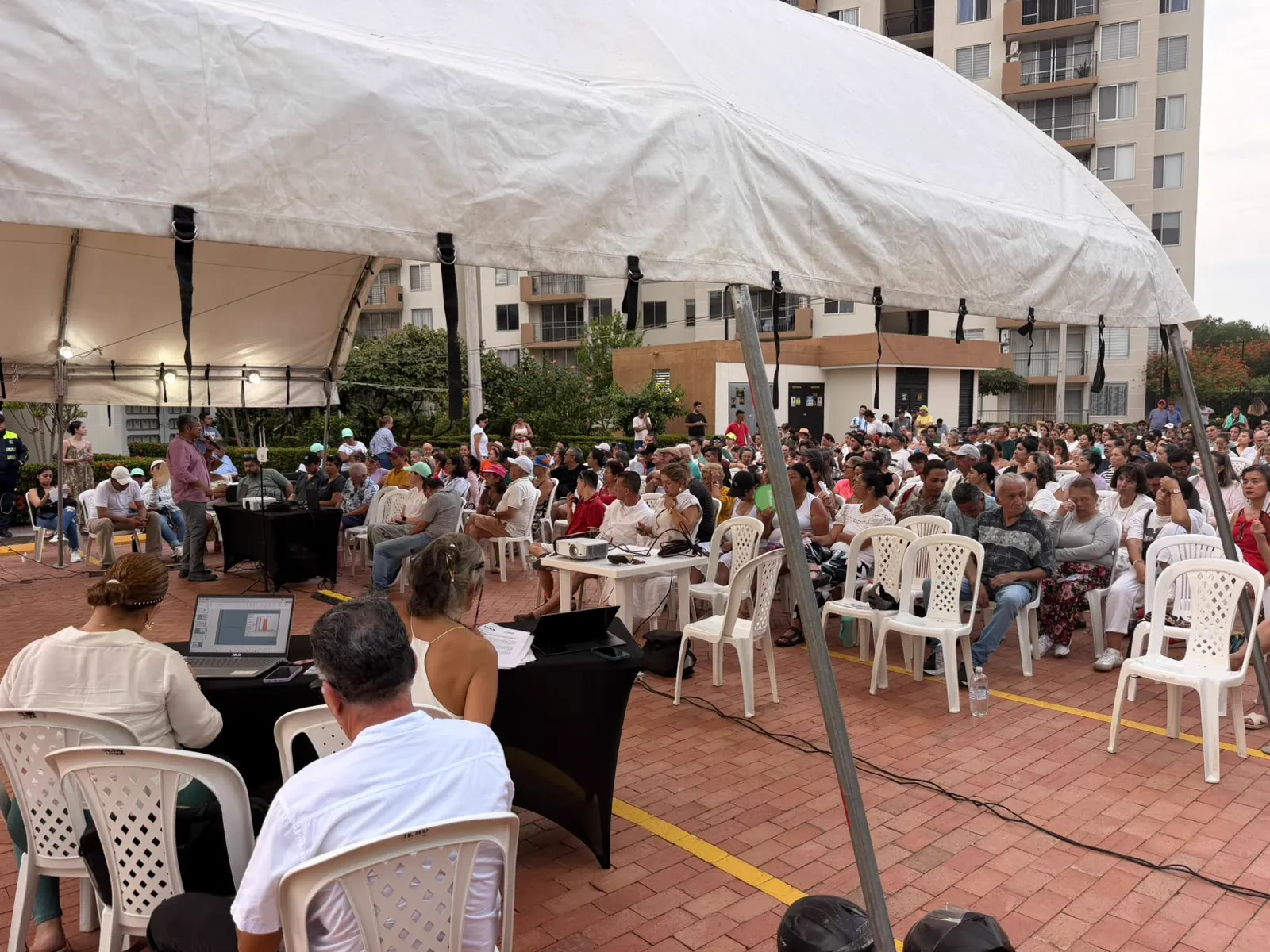 Asamblea bajo carpa en un conjunto residencial, con público sentado